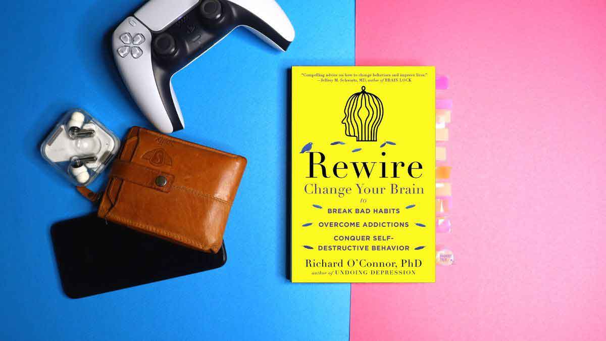 Rewire by Richard O'Connor Paperback book along with PS5 controller, leather wallet, Nothing Ear 1 and Android Smartphone